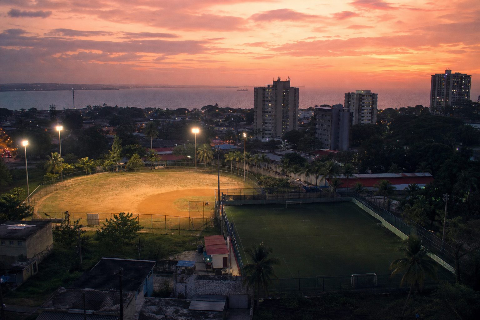 Empty floodlit baseball diamond and football pitch in a Caribbean city at dusk (picture made with AI)