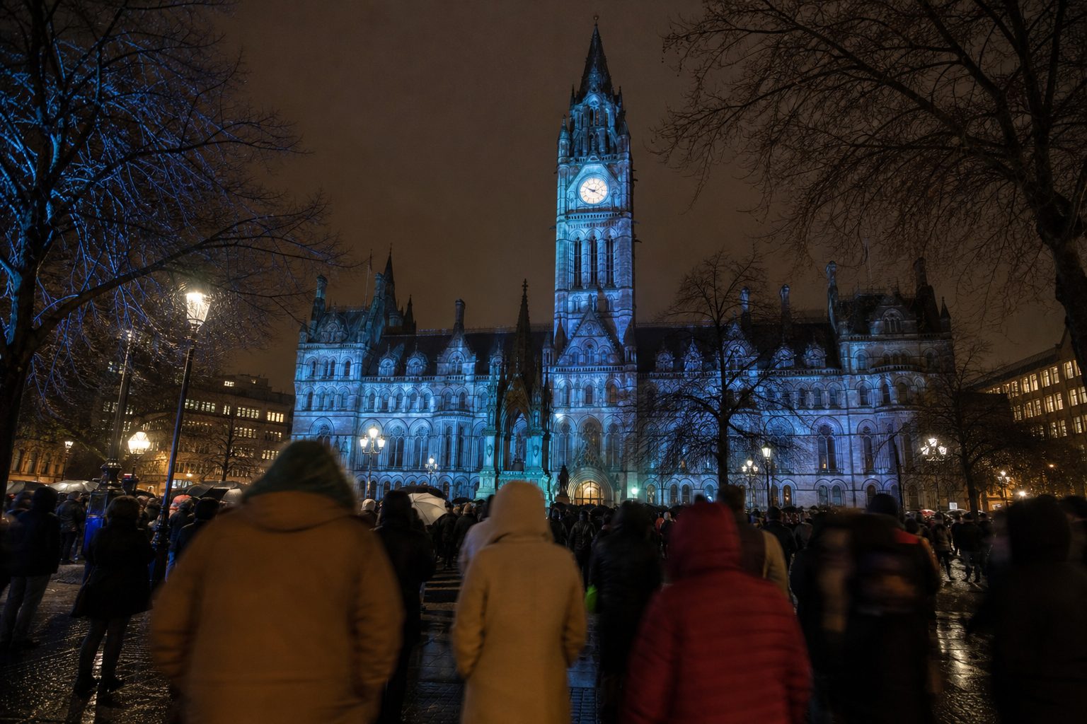 Victorian Gothic town hall tower lit in pale blue light above a crowd at dusk (picture made with AI)