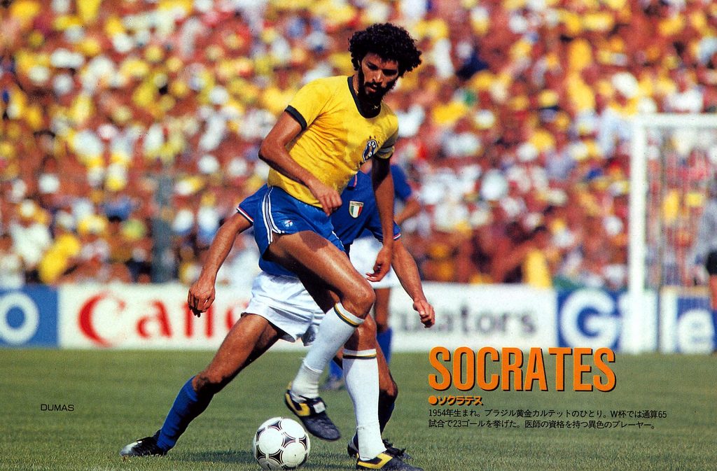 Socrates in a yellow Brazil shirt shielding the ball from an Italy player in blue