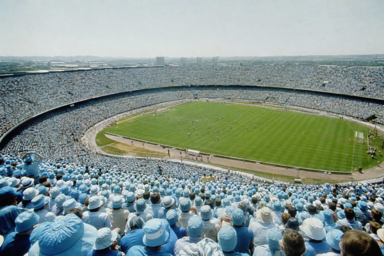 Sea of sky blue scarves in a huge sunlit stadium bowl on cup final day (picture made with AI)