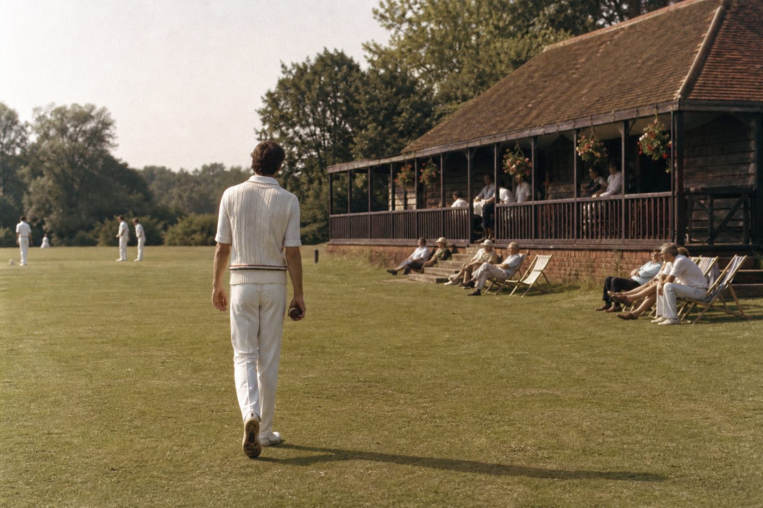 Tall bowler in cricket whites walking back to his mark at a village ground (picture made with AI)