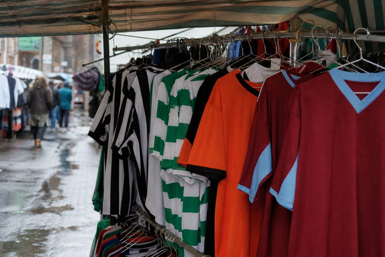 Market stall hung with plain vintage football shirts in stripes and hoops (picture made with AI)