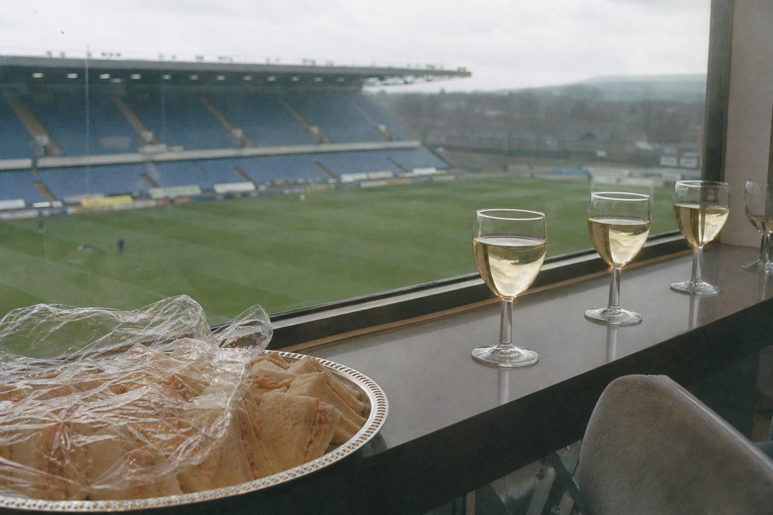 Plate of prawn sandwiches in a hospitality box overlooking a blurred pitch (picture made with AI)